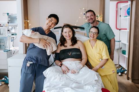 Foto da família reunida com a equipe médica celebrando a chegada da bebê.'