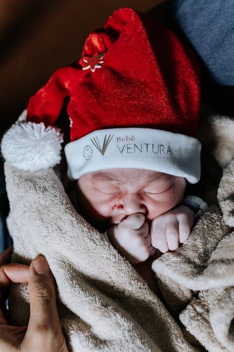 Foto aproximada da recém-nascida com touca de Natal.'