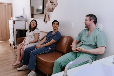 Foto da equipe médica e acompanhante conversando na sala de parto.'