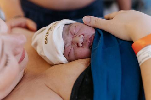 Foto aproximada da bebê descansando no colo da mãe.'