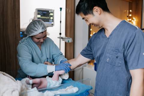 Foto do pai fazendo carimbo do pé da bebê.'