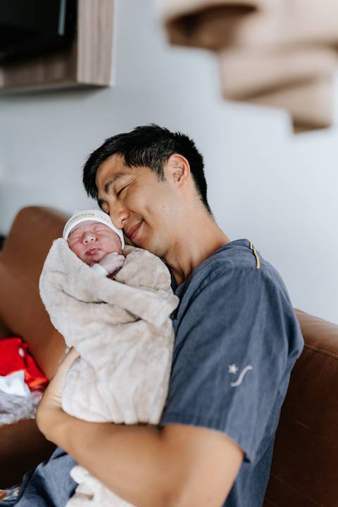 Foto aproximada do pai encostando o rosto na bebê com olhos fechados.'