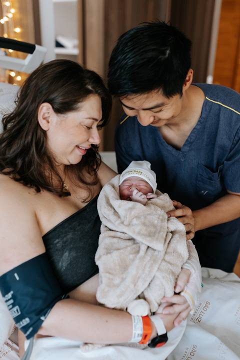 Foto do casal observando a bebê dormindo calmamente.'