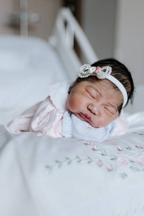 Foto aproximada da bebê com laço em momento de repouso.'