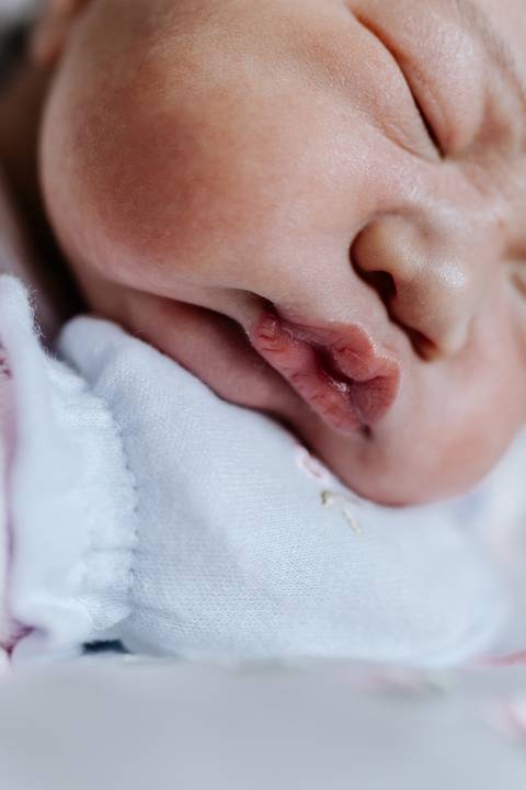 Foto em detalhe da boca da bebê destacando a delicadeza.'