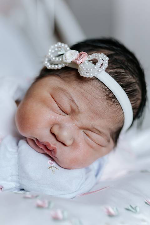 Foto de close do rosto da bebê com foco na expressão serena.'