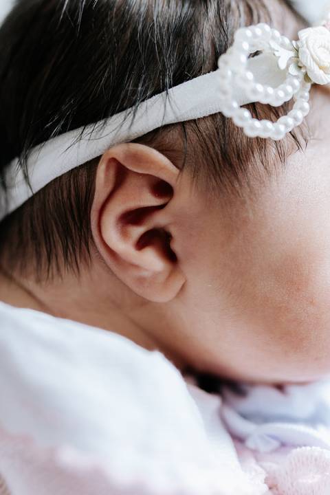 Foto em detalhe da orelha e cabelo da recém-nascida.'