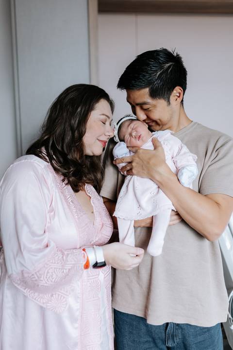 Foto do casal em conexão com a bebê no colo. '