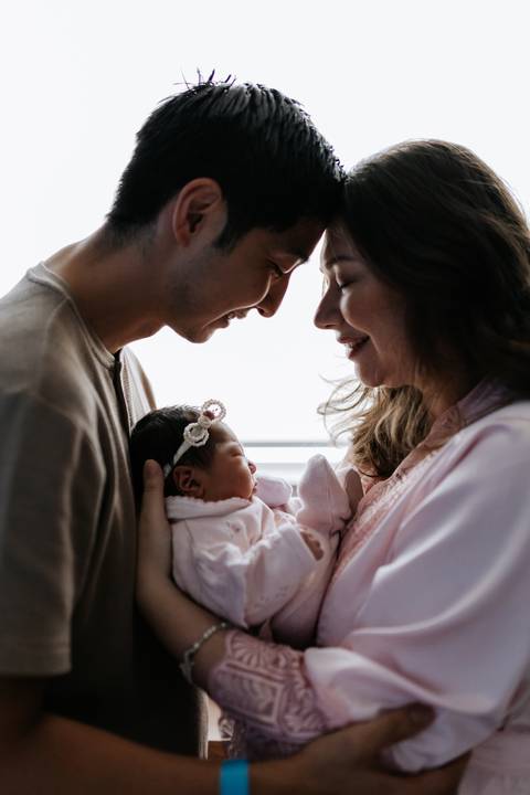 Foto aproximada do casal com os rostos próximos à bebê.'