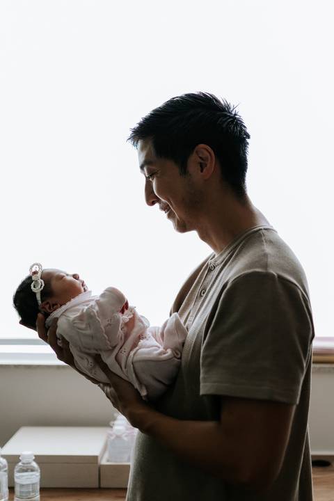 Foto do pai segurando e olhando a bebê. '