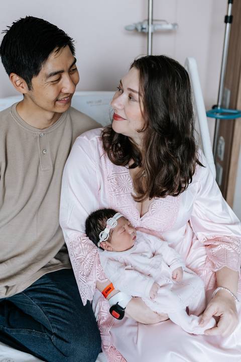 Foto aproximada do casal admirando a bebê dormindo calmamente.'