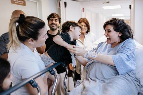 Foto da gestante sorrindo e dando um beijo no filho mais velho antes do parto. '