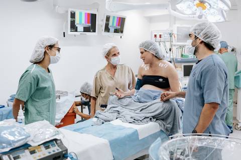 Foto da equipe médica preparando a gestante no centro cirúrgico.'
