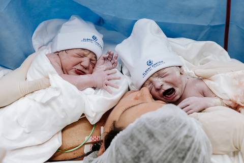 Foto dos gêmeos recém-nascidos chorando logo após o parto.'