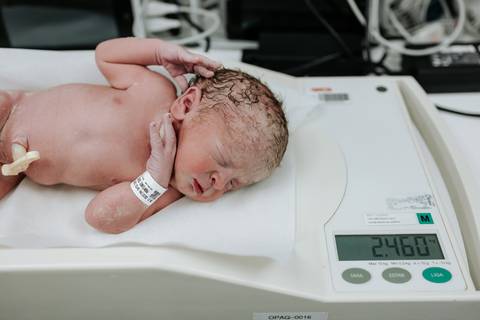 Foto de um dos bebês sendo pesado na balança pediátrica.'
