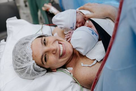 Foto da mãe sorrindo com os dois bebês em momento de felicidade.'