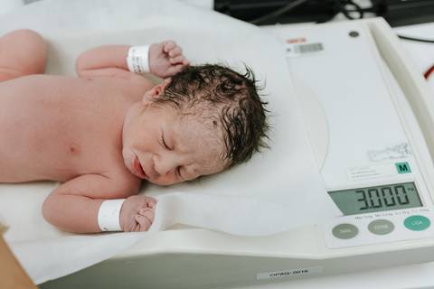 Foto do segundo bebê sendo pesado no berço aquecido.'