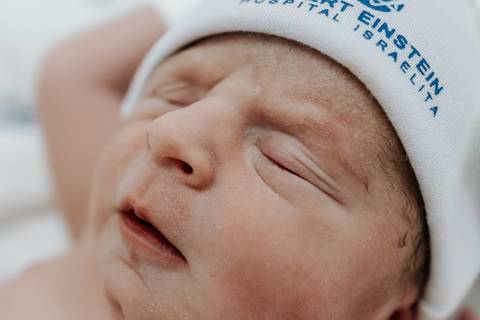 Foto em detalhe do rosto do bebê destacando os traços delicados.'