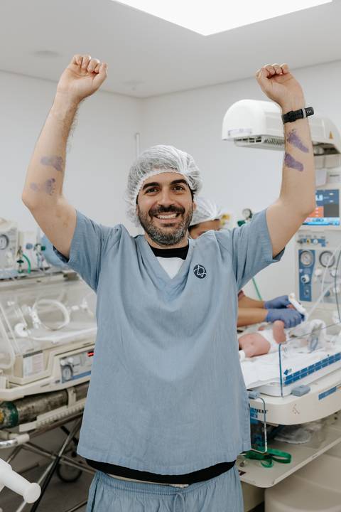 Foto do pai vibrando com os braços erguidos mostrando o carimbo.'