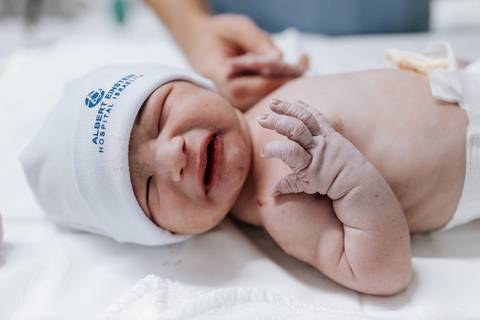 Foto do bebê recebendo os primeiros cuidados da equipe no berço aquecido.'