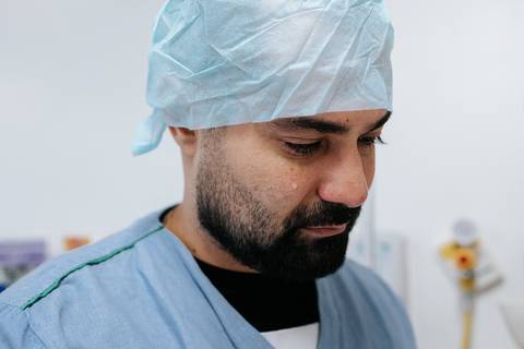 Foto aproximada do pai com olhar sereno e emocionado no centro cirúrgico.'