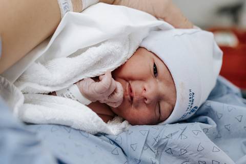 Foto aproximada do recém-nascido descansando no colo materno.'