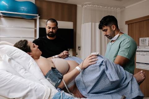 Foto da equipe médica realizando monitoramento na gestante na cama.'