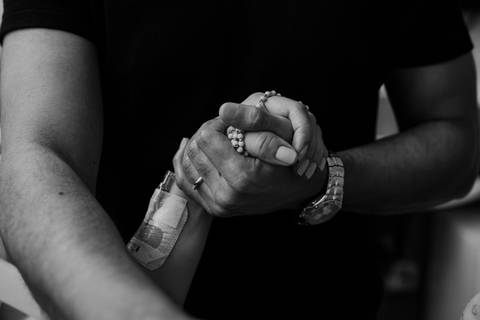 Versão em preto e branco do detalhe das mãos dadas do casal.'