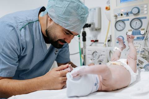 Foto do pai observando o recém-nascido. '