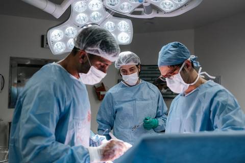 Foto em plano aberto da equipe médica no centro cirúrgico.'