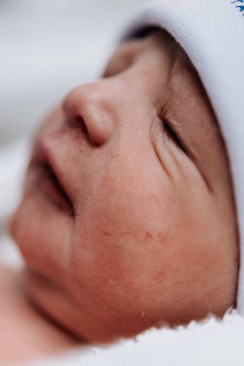 Detalhe em macro do rosto do recém-nascido destacando os traços delicados.'