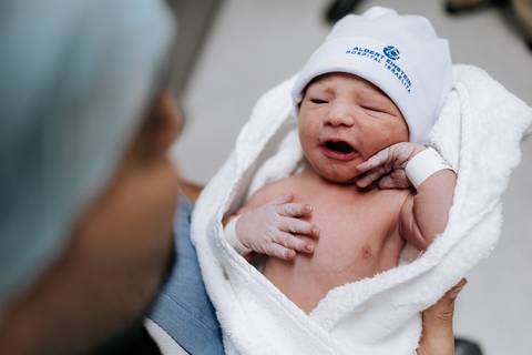 Foto do pai segurando o filho no colo com olhar de proteção e orgulho.'
