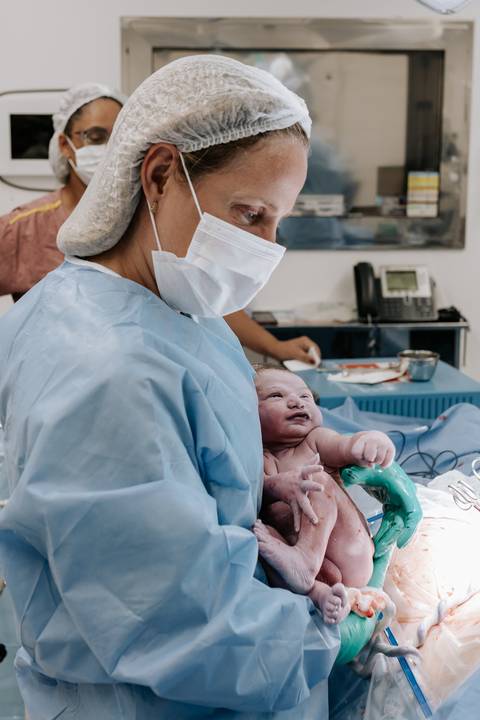 Equipe médica levando o recém-nascido para a mãe. '