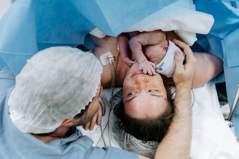 Retrato do casal e bebê sob a luz do centro cirúrgico.'