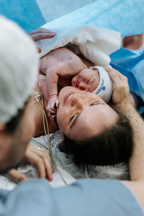 Mãe sorridente com o bebê encostado em sua bochecha.'