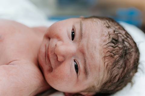 Close do rosto do bebê esboçando um leve sorriso.'