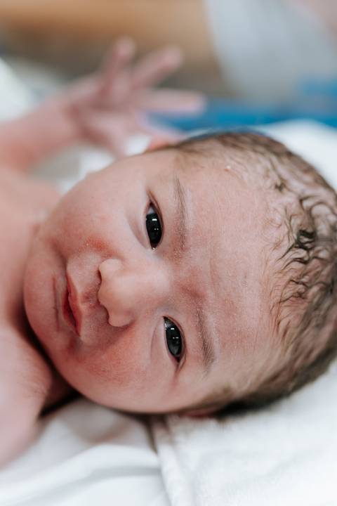 Retrato aproximado do bebê com foco no olhar curioso.'