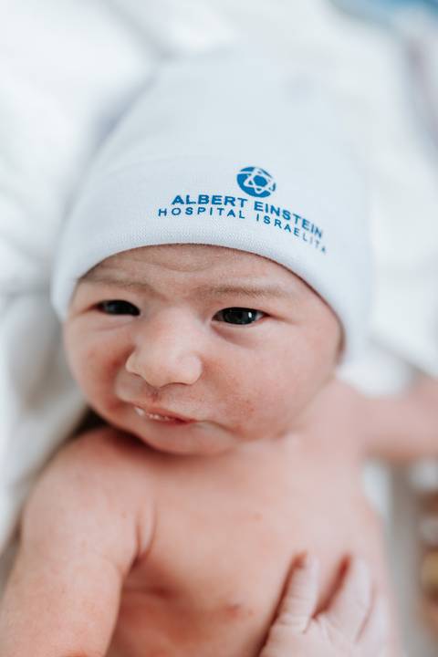 Foto de close do rosto do bebê com a touca personalizada da maternidade.'