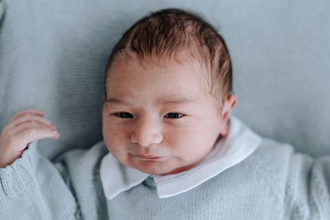 Retrato aproximado do bebê deitado sob luz natural.'