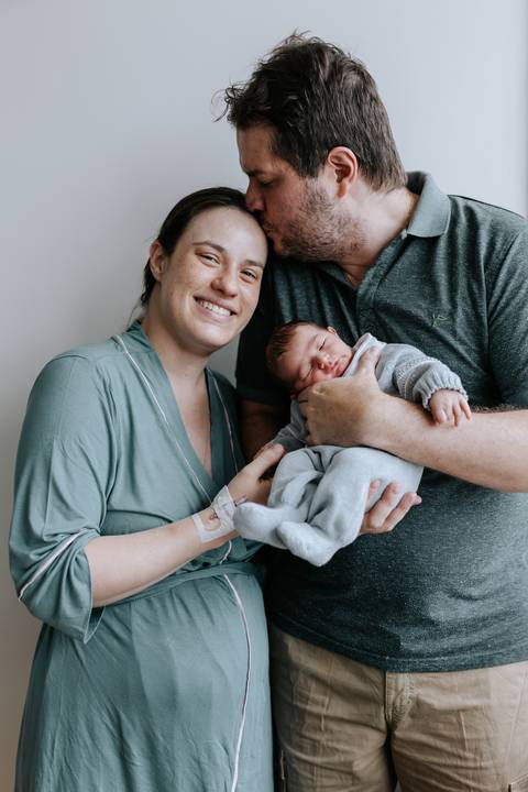 Pais sorrindo com o filho no colo em momento de acolhimento.'