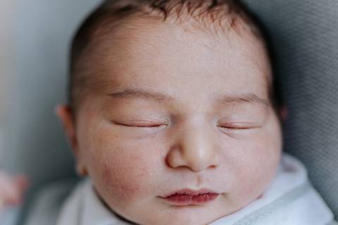 Close frontal do rosto do bebê dormindo.'