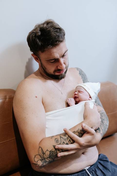 Foto do pai realizando o contato pele a pele com a filha.'