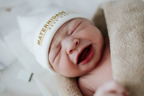 Foto da bebê com touca personalizada da maternidade.'