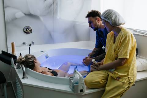 Foto da gestante na banheira com auxílio da equipe.'