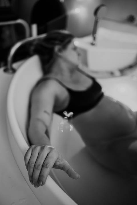 Foto em preto e branco da gestante na banheira.'