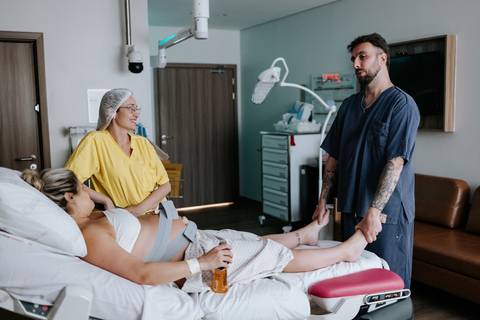 Foto da gestante em conversa com a equipe médica e o pai.
'