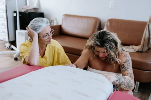 Foto da gestante apoiada na maca fazendo exercícios. '