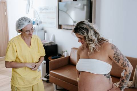 Foto da gestante em pé recebendo orientações da equipe.'