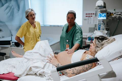 Foto da gestante na maca sendo monitorada pela equipe médica.'