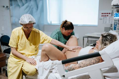 Foto da equipe realizando exame clínico na gestante na maca.'